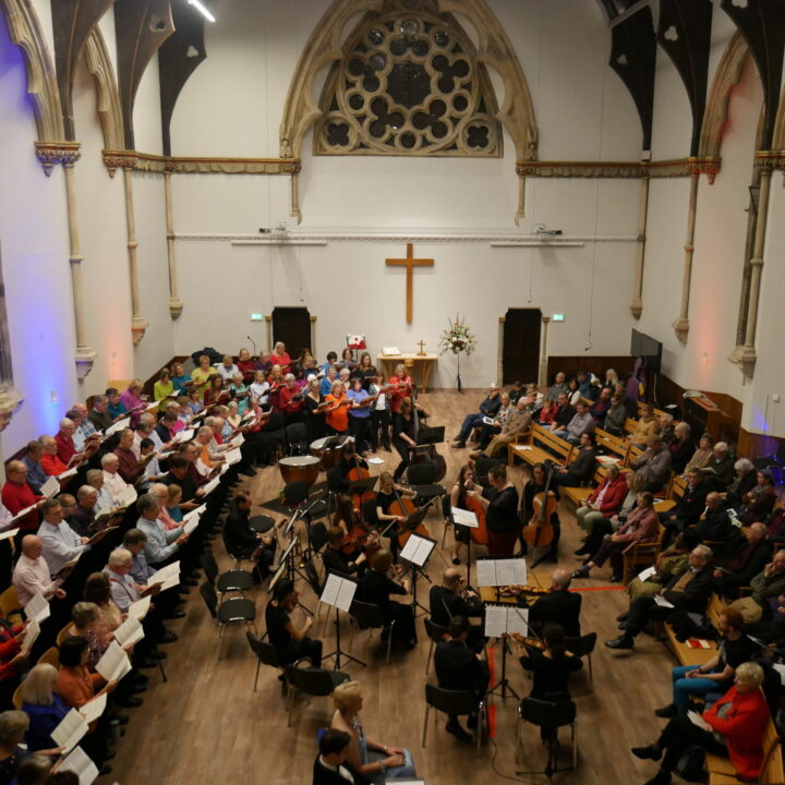 A view of the church from the balcony with singers on the left side, an orchestra in the middle and an audience sitting on the right hand side.